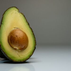 Home Half avocado on gray background, showcasing fresh green and brown hues for food photography.